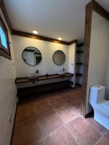 a bathroom with two sinks and a toilet with two mirrors at Casa Mayay in Ranco +12 photos