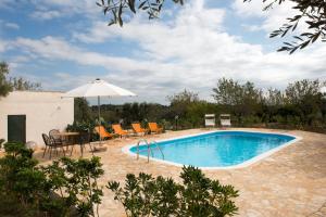 a swimming pool with a table and chairs and an umbrella at Relais Trullo degli Emme in Ostuni