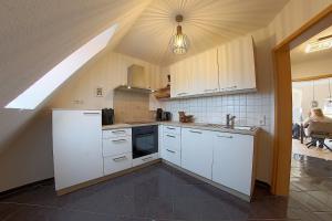 a kitchen with white cabinets and a ceiling with a window at PM09 KüstenReich in Wremen
