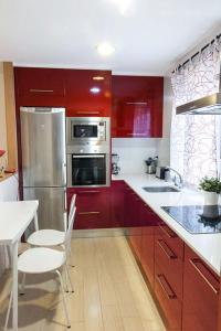 una cocina con armarios rojos y electrodomésticos de acero inoxidable en Apartamento Vitoria, en Vitoria-Gasteiz