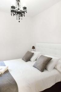 ビトリア・ガステイスにあるApartamento Vitoriaの白い枕とシャンデリアが備わる白いベッド