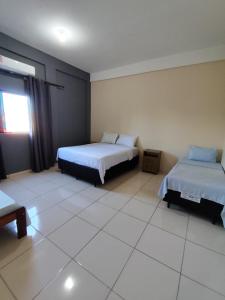a bedroom with two beds and a window at Hotel Oasis 2 in Conceição do Araguaia