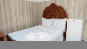 a bed with a wooden headboard and two wedding rings on it at Hotel Oasis 2 in Conceição do Araguaia +7 photos
