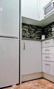 a kitchen with white cabinets and a refrigerator at Mar & Sol Pineda in Pineda de Mar +8 photos