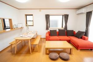 a living room with a red couch and a table at Max13ppl Family-Friendly , 110sqm , SpaciousLiving&4BRM , LongStay OK , 2CarPark , 25min to NAGOYA & LEGO & Outlet in Yatomi 