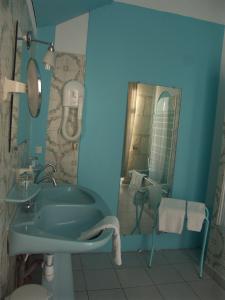 uma casa de banho azul com um lavatório e um espelho em Hôtel du Palais em Angoulême