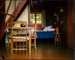 a bedroom with a bed and a table and chairs at Pousada Paraíso das Araucárias Monte Verde Vista das montanhas in Monte Verde