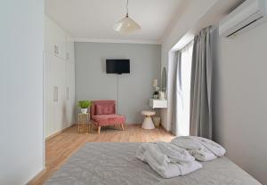 a white bedroom with a bed and a red chair at Galaris' Studio in Samos
