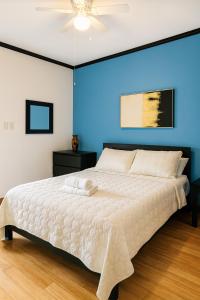 a bedroom with a white bed with a blue wall at Emmanuelli Sur 7 Bedroom Mall of San Juan Home in San Juan