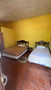 two beds in a room with a yellow wall at Accommodation in Copán Ruinas #6 in Copán Ruinas