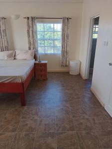 a bedroom with a bed and a tiled floor at Fijay Bay Inn in Carriacou
