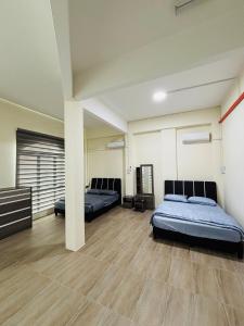 two beds in a room with wooden floors at May Ong Guest House in Taiping