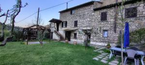 a stone house with a table and chairs in a yard at Casa Biscarello - Borgo e Lago in Grotte di Castro
