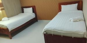 a bedroom with two beds with white sheets at Hotel Cristina in Bocas Town