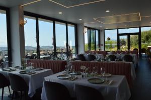 a restaurant with white tables and chairs and windows at Hôtel Casa Matteu in Afa