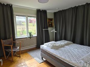 a bedroom with a bed and a chair and a window at Lägenhet i Sandhem in Sandhem