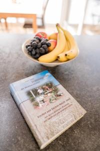 a bowl of fruit sitting next to a book at Ferienhaus Brückenblick 12 a in Fehmarnsund +26 photos