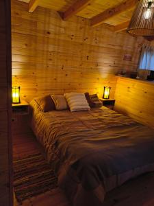 a large bed in a wooden room with two lamps at Alma de Puelo in Lago Puelo