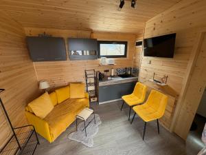 a living room with yellow furniture and a kitchen at The Little House in Sohodol