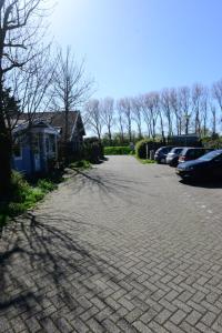 a brick driveway with cars parked on the side of it at Tussen duin en dijk in Warmenhuizen