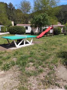 a picnic table and a red slide in a yard at Mobil home LE COUCOU in Le Martinet