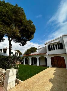 a white house with a tree in the yard at Los Caballos Villa in Cala Galdana