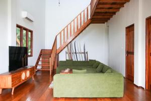 a living room with a green couch and a staircase at Villa Ombak in Katiet