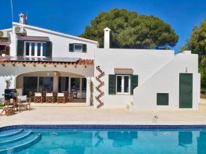 a villa with a swimming pool in front of a house at Los Caballos Villa in Cala Galdana