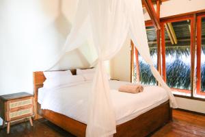 a bedroom with a bed with a mosquito net at Villa Ombak in Katiet
