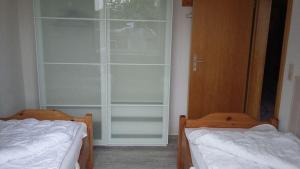 a bedroom with two beds and a glass closet at FeWo-mit-Terasse-u-Garten-am-Golfplatz in Wulfen auf Fehmarn