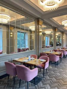 a restaurant with wooden tables and pink chairs at The Supreme Hotel and Banquet in Gaya