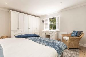 a bedroom with a bed and a chair and a window at Maroon Belles in Cape Town