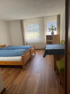 a bedroom with two beds and a table and two windows at Hotel ilufa in Meiringen +18 photos