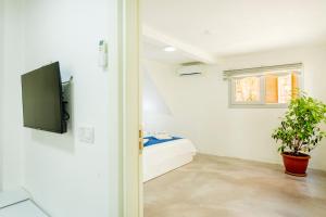 a room with a bed and a tv on a wall at Westcoast Kalkan Suites 1-bedroom suite located heart of Kalkan Old Town in Kalkan