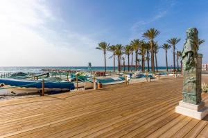 a boardwalk with boats and palm trees on the beach at Todimer Costa Peñon in Torrenueva