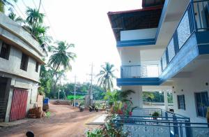 a building with blue balconies and a dirt road at Joy Villa Homestay in Honāvar