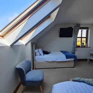 a attic room with two beds and a chair at Boherbui B&B in Doolin