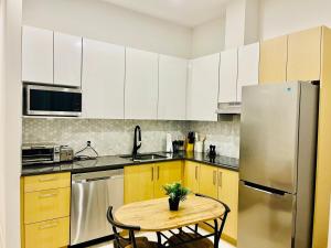 a kitchen with a table and a stainless steel refrigerator at Modern Ground Level 1BR Apartment - Prime Location in North Vancouver