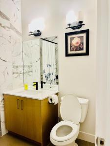 a bathroom with a toilet and a sink and a mirror at Modern Ground Level 1BR Apartment - Prime Location in North Vancouver
