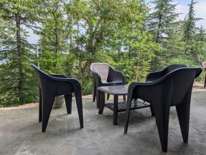 four black chairs and a table on a patio at Deodar hill top home stay chail in Chail