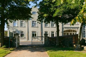 a white building with a gate in front of it at Hotel Goldener Fasan in Oranienbaum-Wörlitz