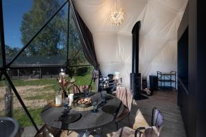 a tent with a table and chairs and a chandelier at Līgo glamping in Stacija Meitene