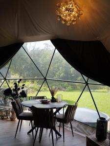 a table and chairs in a tent with a tub at Līgo glamping in Stacija Meitene +16 photos