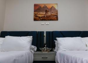 two beds with white sheets and a picture of the pyramids at Grand pyramids view & Jacuzii in Cairo