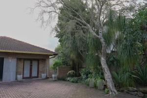 a house with a tree next to a brick driveway at Son Heuwel B&B room in Nelspruit