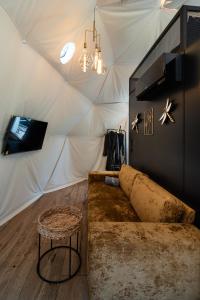 a living room with a couch in a tent at Līgo glamping in Stacija Meitene