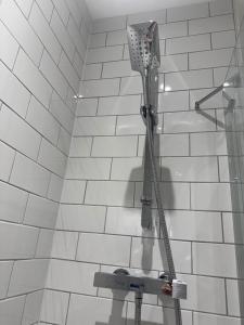 a shower head in a white tiled bathroom at Blissful Abode in Birmingham