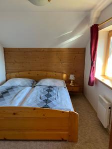 a bedroom with a wooden bed and a window at Chata Dolce in Trutnov