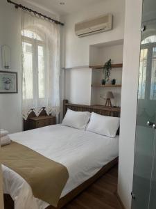 a bedroom with a bed with white sheets and windows at Bademli Ancanoz Hotel in Dikili