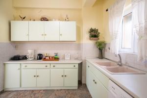 a kitchen with white cabinets and a sink and a window at Potami Studios in Lefkimmi +53 photos